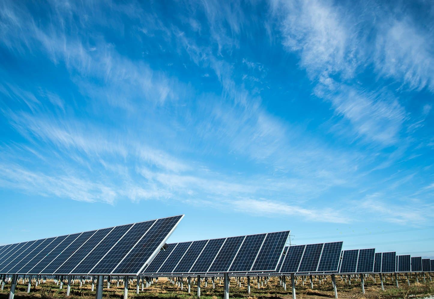 Parque de placas solares sob céu azul com nuvens